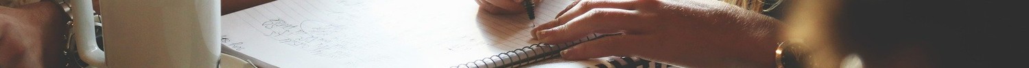 mehrere Personen sitzen rund und einem Tisch, eine Person macht Notizen auf einem Papierblock