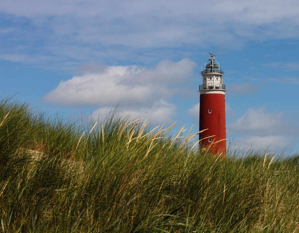 grüne Düne, blauer Himmel, roter Leuchtturm