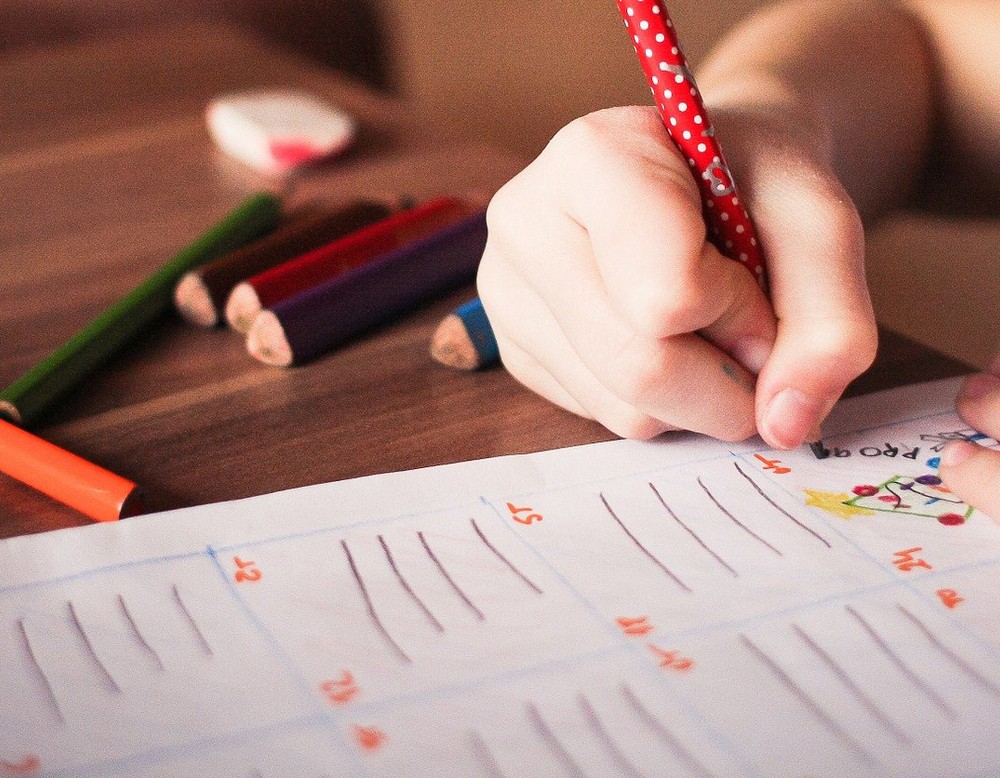 Kind, das mit einem roten Stift ein Arbeitsblatt bearbeitet